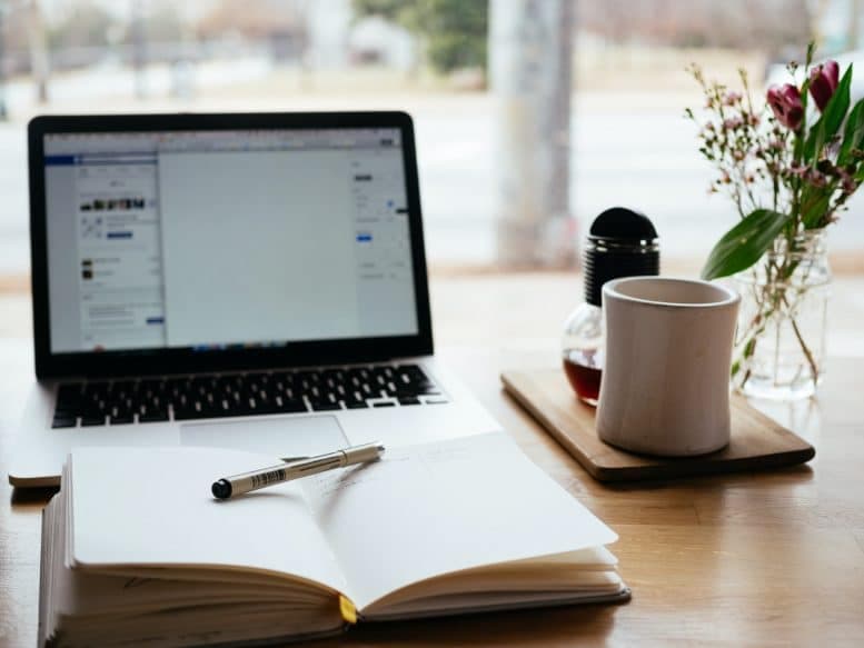 Ordinateur portable ouvert sur un bureau avec un carnet, un stylo et une tasse